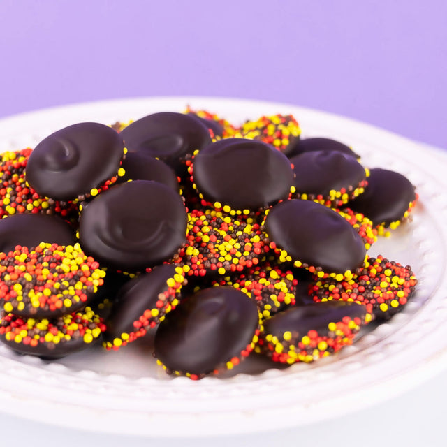 Handcrafted dark chocolate nonpareils topped with festive autumn sprinkles – gourmet seasonal fall candy from Nibbles & Bits.