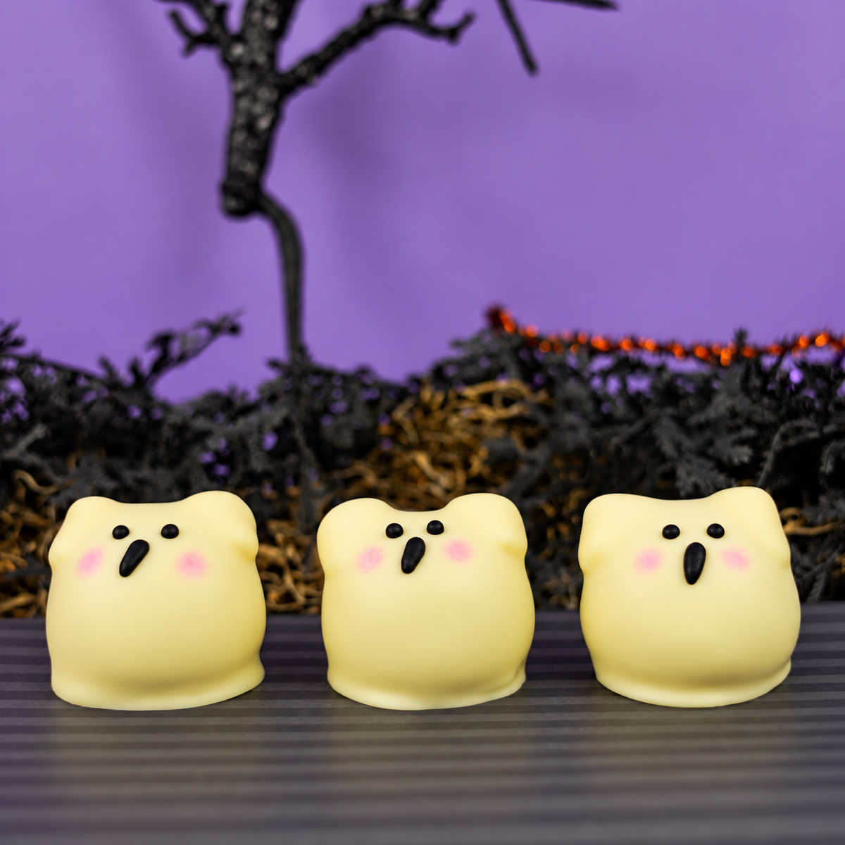 Three Ghost Ganache Truffles arranged together showing their marshmallow arm shapes and painted ghost faces.