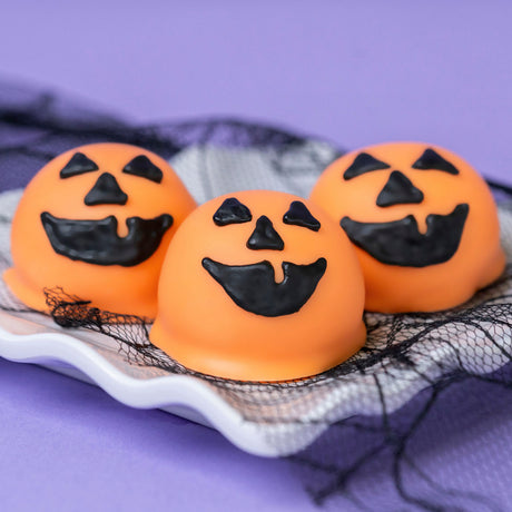 Box of six milk chocolate ganache truffles dipped in orange white chocolate with hand-drawn jack-o-lantern faces – handmade Halloween candy from Nibbles & Bits in Scranton, PA.