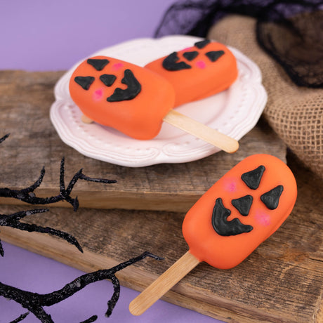 Jack-o-lantern cookie dough pop coated in smooth white chocolate – festive handmade Halloween candy treat from Nibbles & Bits in Scranton, PA.