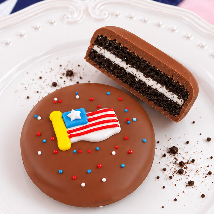 Patriotic milk chocolate covered Oreo showing dark chocolate cookie layers and white cream filling, handcrafted Fourth of July treat by Nibbles and Bits Scranton PA.