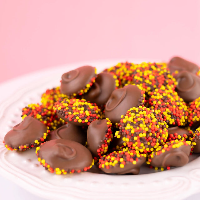 Handcrafted milk chocolate nonpareils topped with festive autumn sprinkles – gourmet seasonal fall candy from Nibbles & Bits.