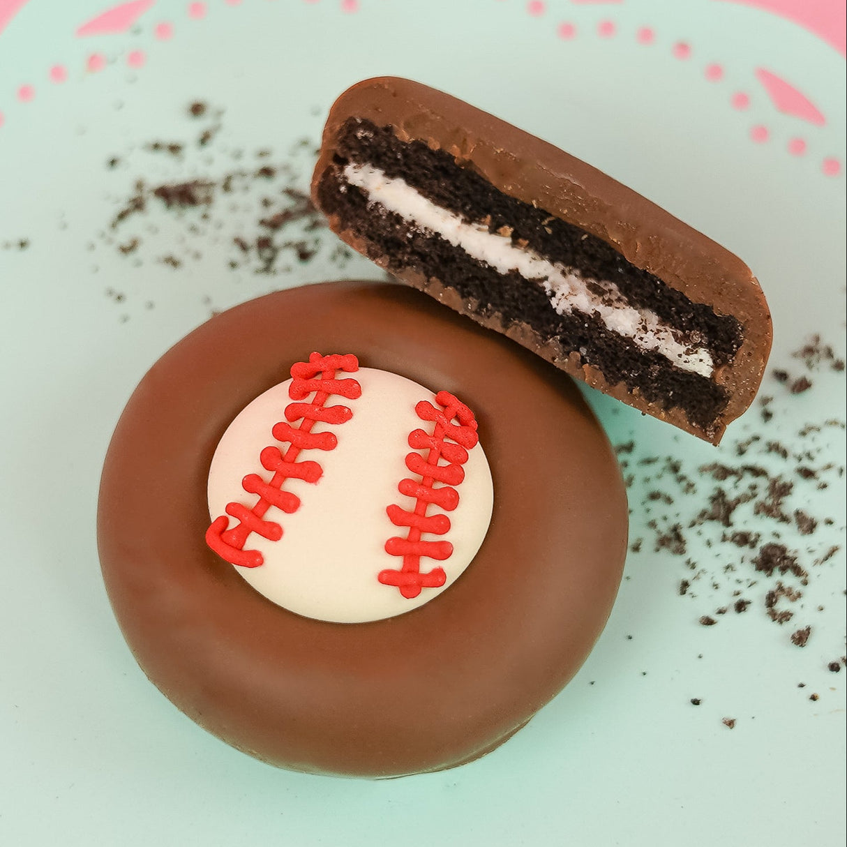 Milk chocolate baseball Oreo with dark chocolate cookie layers and white cream filling on a mint green plate, handcrafted sports themed chocolate gift by Nibbles and Bits Scranton PA.