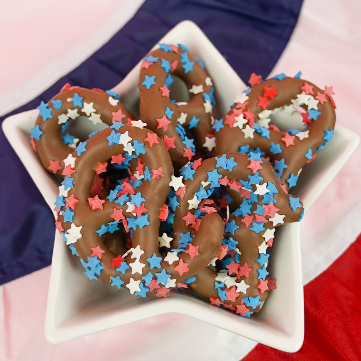 Bite sized milk chocolate pretzel pieces covered in red white and blue star confetti sprinkles, patriotic summer snack handmade in Scranton Pennsylvania by Nibbles and Bits.