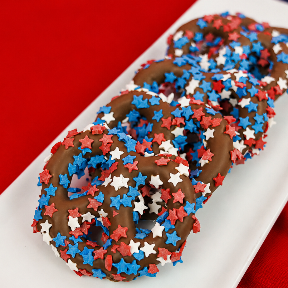 Milk chocolate covered pretzel blanketed in red white and blue star shaped sprinkles, festive patriotic snack handmade in Scranton Pennsylvania by Nibbles and Bits.