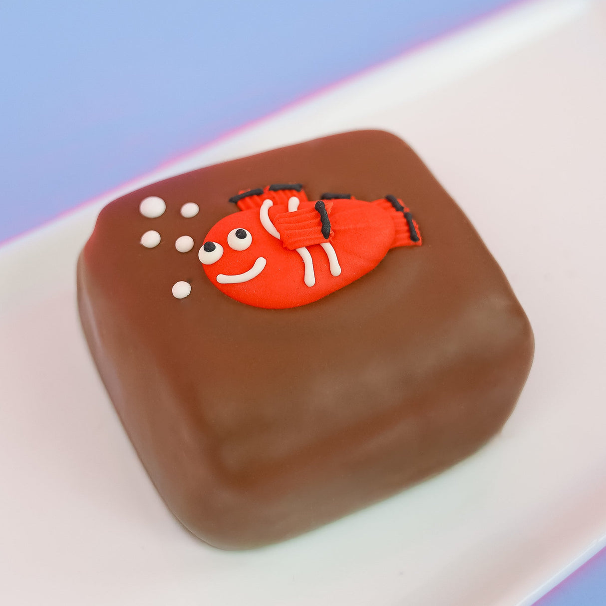 Milk chocolate s'more decorated with a smiling orange and white fondant clownfish with black fin details and white bubble decorations, handmade ocean themed treat by Nibbles and Bits Scranton Pennsylvania.