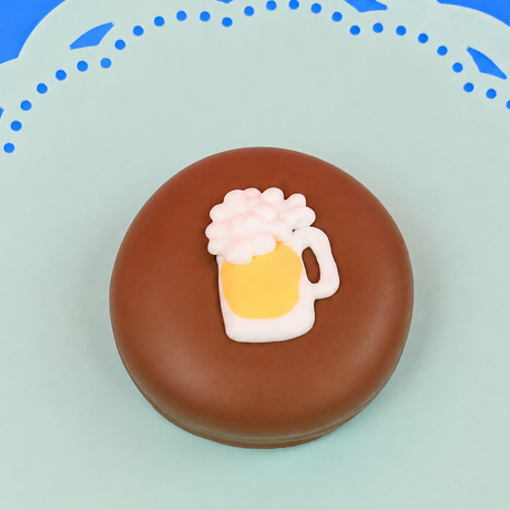Single milk chocolate covered Oreo decorated with a fondant beer mug overflowing with white frothy foam on a mint green decorative plate with blue background, handmade adult novelty gift by Nibbles and Bits Scranton PA.