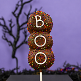 A single Boo! Marshmallow Pop on a stick, dipped in milk chocolate, covered in Halloween nonpareils, and spelling out "BOO" in white icing.