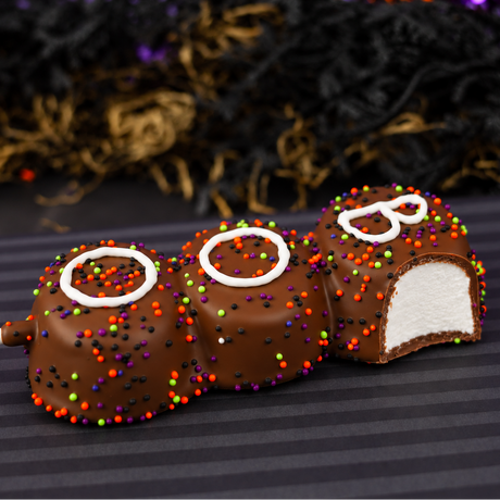 Boo! Marshmallow Pop lying on its side with one marshmallow cut open to reveal soft vanilla marshmallow inside the milk chocolate shell.