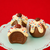 A patriotic sundae milk chocolate ganache truffle revealing a rich creamy milk chocolate ganache center alongside two whole decorated truffles on a mint green cake stand, handcrafted patriotic gift by Nibbles and Bits Scranton PA.