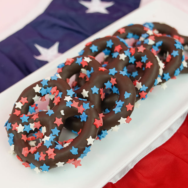 Dark chocolate covered pretzel blanketed in red white and blue star shaped sprinkles, bold patriotic snack handmade in Scranton Pennsylvania by Nibbles and Bits.