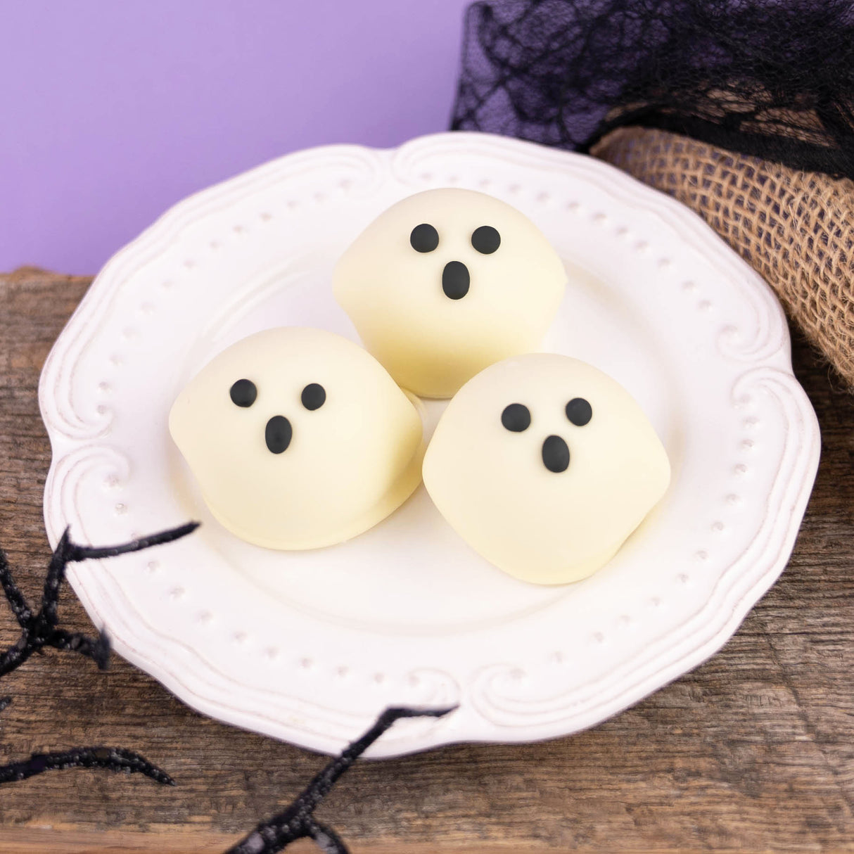 Ghost truffle made with milk chocolate ganache dipped in smooth white chocolate and decorated with a hand-drawn ghost face – handmade Halloween candy from Nibbles & Bits in Scranton, PA.