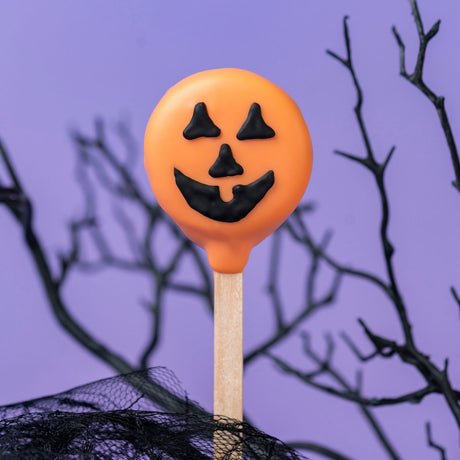 Nabisco Oreo cookie covered in orange chocolate with a hand-drawn jack-o-lantern face – festive handmade Halloween treat from Nibbles & Bits in Scranton, PA.