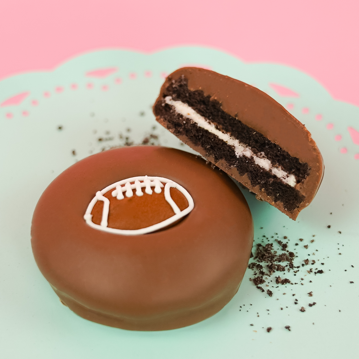 Milk chocolate football Oreo with dark chocolate cookie layers and white cream filling on a mint green plate, handcrafted sports themed chocolate gift by Nibbles and Bits Scranton PA.