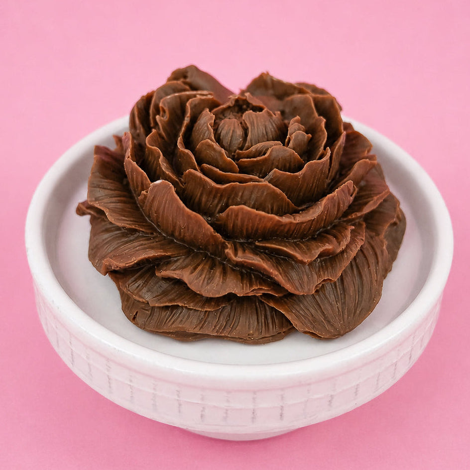 Stunning molded milk chocolate peony flower with detailed ruffled petals in full bloom displayed in a white bowl with pink background, handmade Mother's Day gift by Nibbles and Bits Scranton PA.