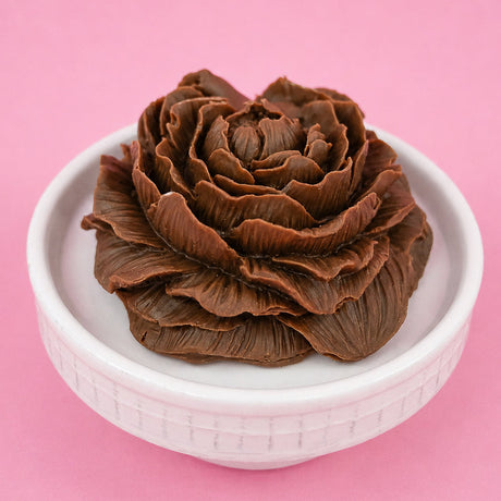 Stunning molded milk chocolate peony flower with detailed ruffled petals in full bloom displayed in a white bowl with pink background, handmade Mother's Day gift by Nibbles and Bits Scranton PA.