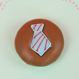 Single milk chocolate covered Oreo decorated with a light blue fondant necktie with hand-piped red diagonal stripes on a mint green decorative plate with pink background, handmade Father's Day gift by Nibbles and Bits Scranton PA.