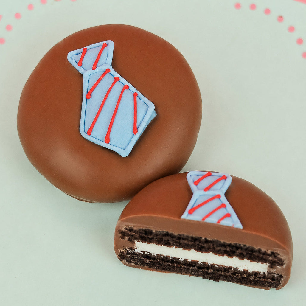 Milk chocolate tie Oreo showing dark chocolate cookie layers and white cream filling alongside whole decorated cookie on a mint green plate, handcrafted Father's Day chocolate gift by Nibbles and Bits Scranton PA.