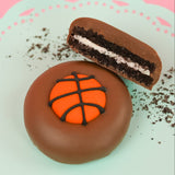 Milk chocolate basketball Oreo showing dark chocolate cookie layers and white cream filling on a mint green plate, handcrafted sports themed chocolate gift by Nibbles and Bits Scranton PA.