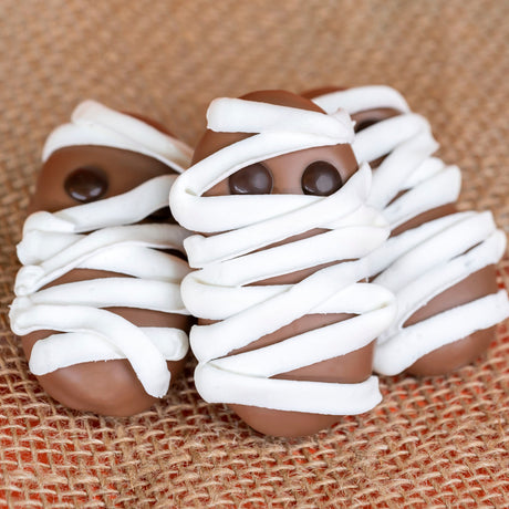 Milk chocolate covered Nutterbutter cookie draped in white chocolate or royal icing with two milk chocolate M&M eyes – handmade Halloween treat from Nibbles & Bits in Scranton, PA.