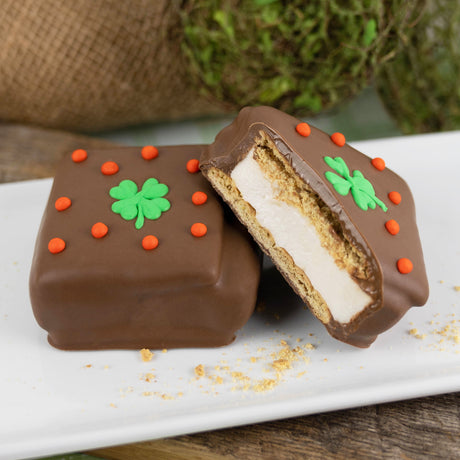 Milk chocolate–covered s’more made with Honey Maid graham crackers and handmade vanilla marshmallow, decorated with a shamrock for St. Patrick’s Day.