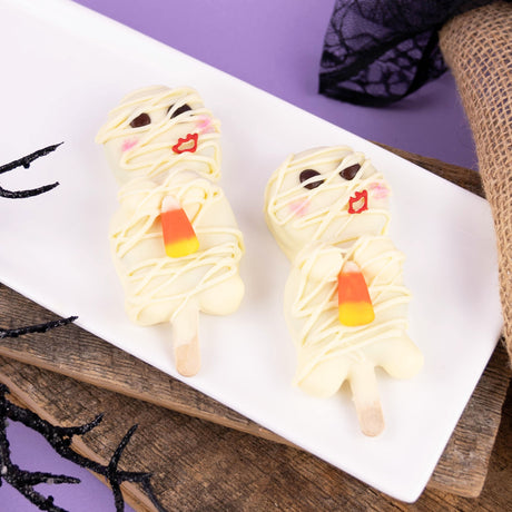 White chocolate covered Nabisco Oreo cookies decorated as spooky mummies holding candy corn – handmade Halloween cookies from Nibbles & Bits in Scranton, PA.