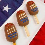 A patriotic milk chocolate peanut butter pop revealing a thick creamy handmade peanut butter ganache center encased in smooth milk chocolate with star confetti decoration, gourmet summer treat by Nibbles and Bits Scranton PA.