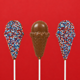 Three solid milk chocolate patriotic ice cream cone pops on white sticks against a bold red background showing both the red, white and blue nonpareil covered side and the detailed molded waffle cone and scoop side, handmade Fourth of July treat by Nibbles and Bits Scranton PA.
