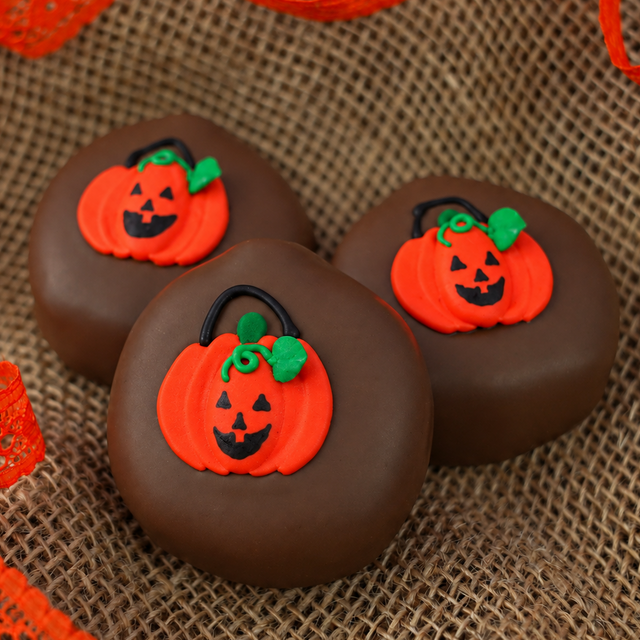 Three Milk Chocolate Peanut Butter Pumpkins on burlap with orange lace ribbon, each topped with a hand-painted trick-or-treat bag decal.