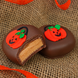 Milk Chocolate Peanut Butter Pumpkin cut in half revealing creamy peanut butter filling, next to a whole pumpkin candy decorated with a trick-or-treat bag design.