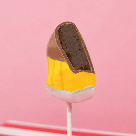 Cross-section of a milk chocolate ganache truffle pencil pop revealing rich creamy ganache center beneath hand-painted chocolate shell, handcrafted teacher appreciation treat by Nibbles and Bits Scranton PA.