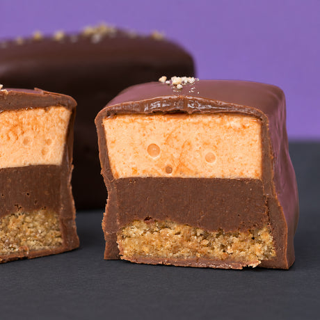 Pumpkin marshmallow smore dipped in chocolate and cut open on a purple background. 