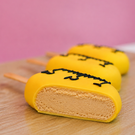 Cross-section of a ruler peanut butter pop revealing rich homemade peanut butter crème center beneath yellow chocolate ruler shell, handcrafted back to school treat by Nibbles and Bits Scranton PA.