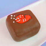 Milk chocolate s'more decorated with a smiling orange and white fondant clownfish with black fin details and white bubble decorations, handmade ocean themed treat by Nibbles and Bits Scranton Pennsylvania.