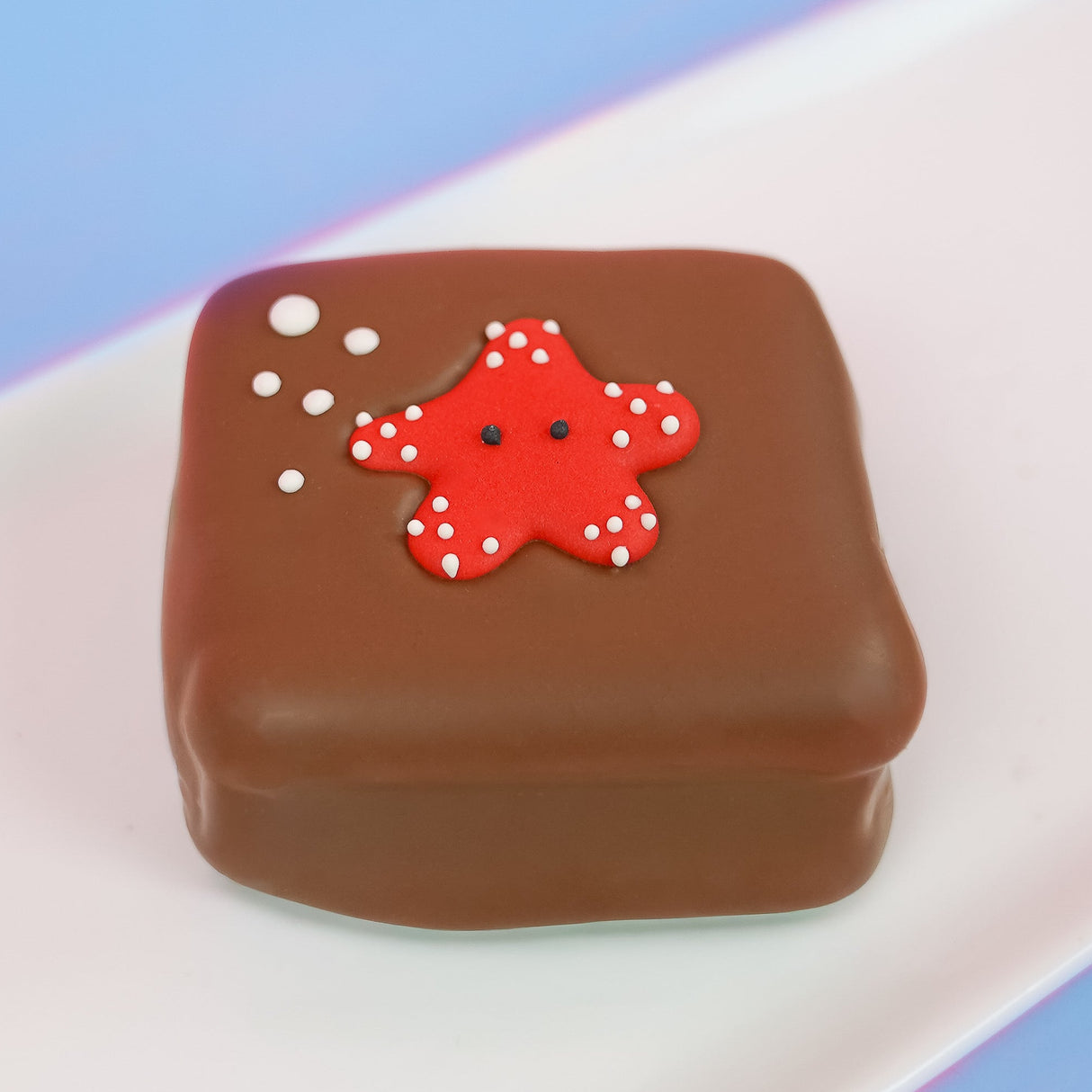 Milk chocolate s'more topped with a cute red fondant starfish covered in white polka dots with black eyes and white bubble details, handmade ocean party favor by Nibbles and Bits Scranton PA.