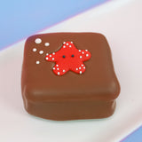 Milk chocolate s'more topped with a cute red fondant starfish covered in white polka dots with black eyes and white bubble details, handmade ocean party favor by Nibbles and Bits Scranton PA.