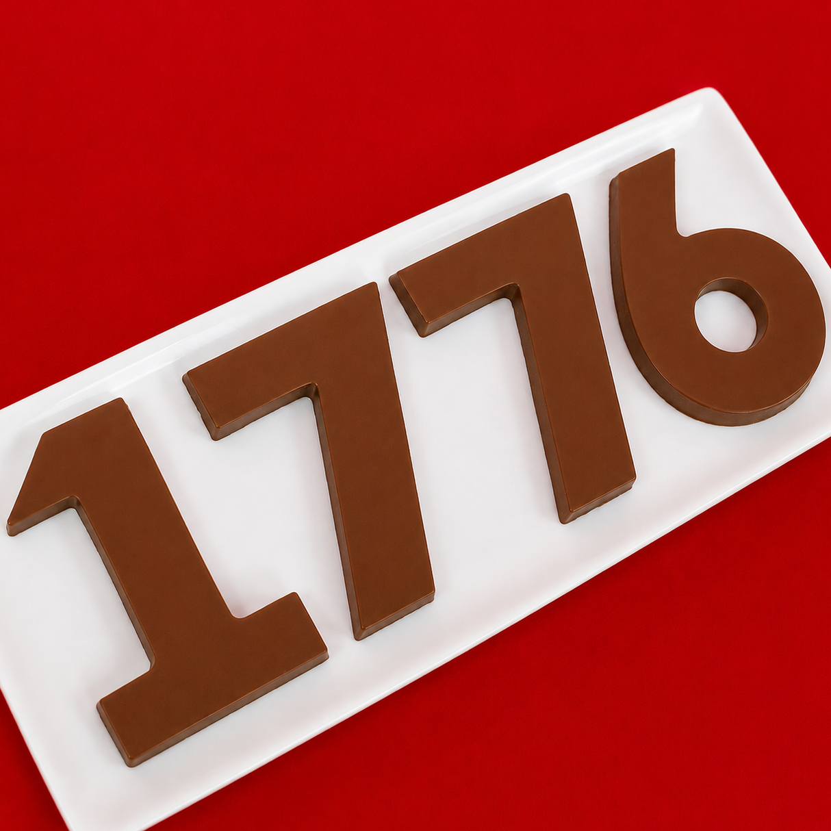 Four solid milk chocolate numbers spelling 1776 displayed on a white rectangular plate against a bold red background, handmade Fourth of July gift set by Nibbles and Bits Scranton PA.