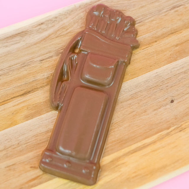 Solid milk chocolate golf bag with detailed molded clubs, pockets and straps displayed on a rustic wood board with pink background, handmade gift for golfers by Nibbles and Bits Scranton PA.