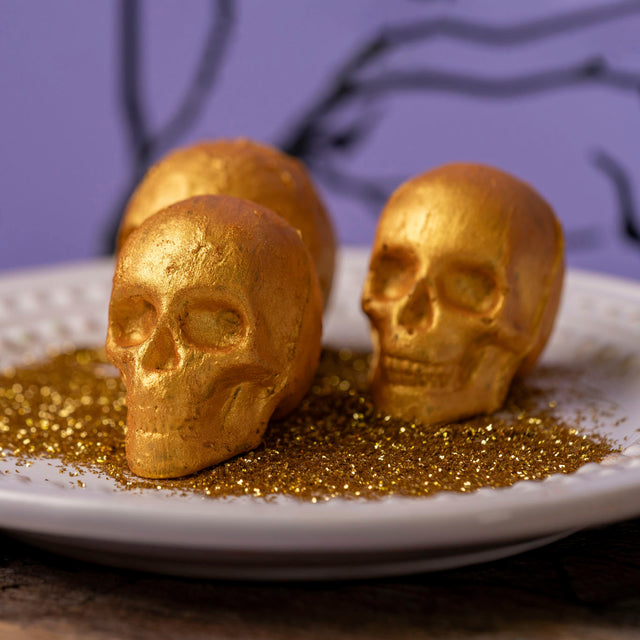 Set of three solid milk chocolate skulls hand-decorated with edible gold shimmer, wrapped in a clear cellophane bag with a bow – Halloween candy from Nibbles & Bits in Scranton, PA.